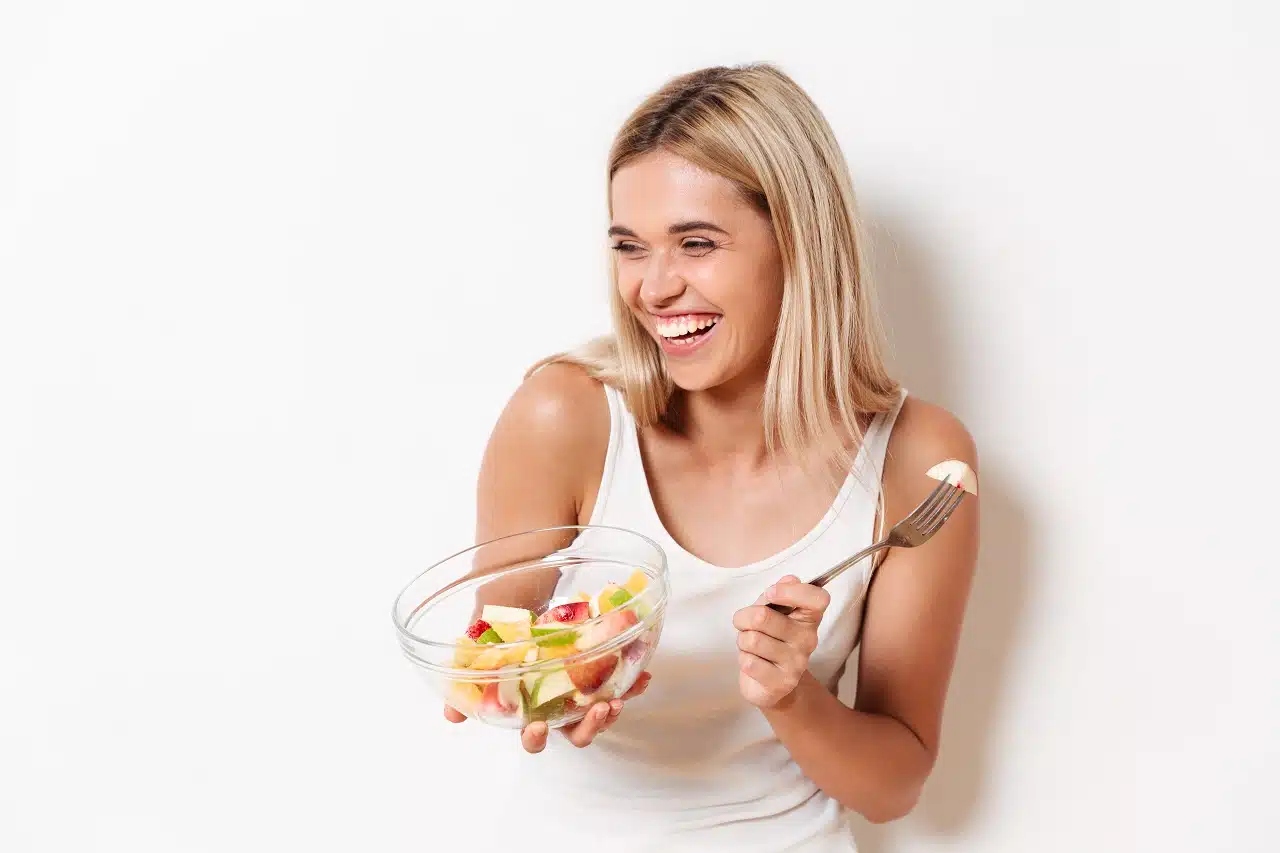 Uśmiechnięta kobieta jedząca sałatkę